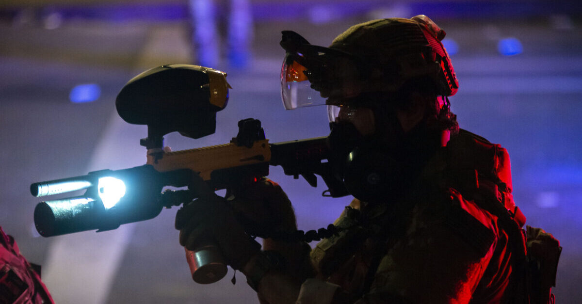 PORTLAND, OR - JULY 22: A federal office points a pepperball gun at a protester while dispersing a crowd in front of the Mark O. Hatfield U.S. Courthouse on July 22, 2020 in Portland, Oregon. State and city elected officials have called for the federal officers to leave Portland as clashes between protesters and federal police continue to escalate.