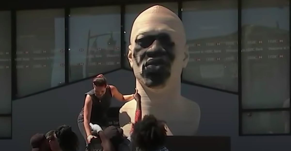 Volunteers clean the George Floyd statue in Brooklyn that was vandalized Thursday
