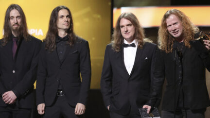 Members of the band Megadeth are wearing suits and tuxedos as they stand on stage at the 2017 Grammy Awards.