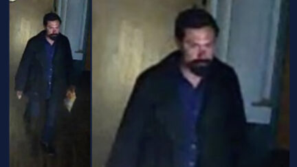 A man with dark hair, beard, and mustache is seen on surveillance camera.