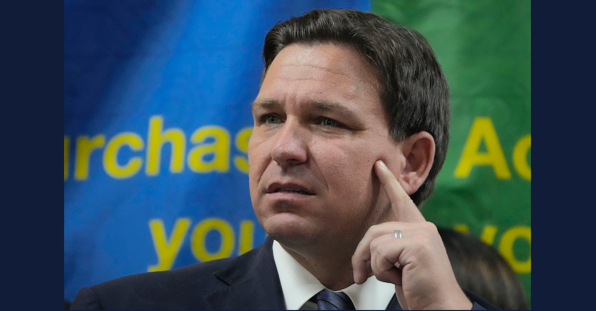 Ron DeSantis covers his face with his hand.