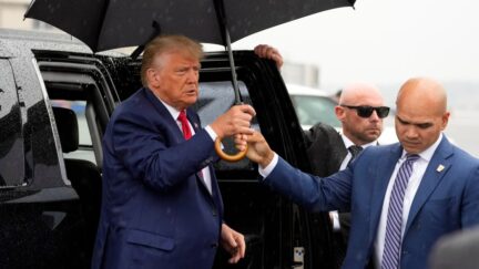 Valet Walt Nauta hands former President Donald Trump an umbrell