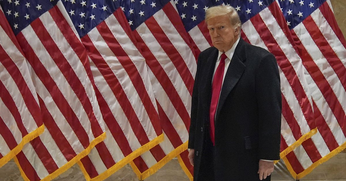 Donald Trump grimaces in front of several flags